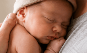 Newborn asleep in fathers arms